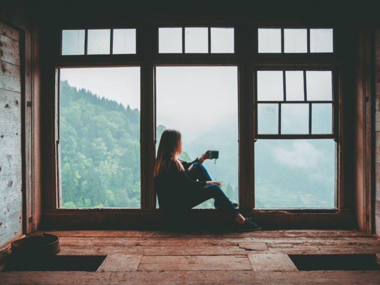 Kobieta siedzi na oknie z kawa. Obrazek w artykule Kawa a antybiotyk. Wyjaśniamy czy należy unikać tego połączenia